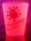 [Tropicana shotglass -- glowing in blacklight (out of focus, dark background)]